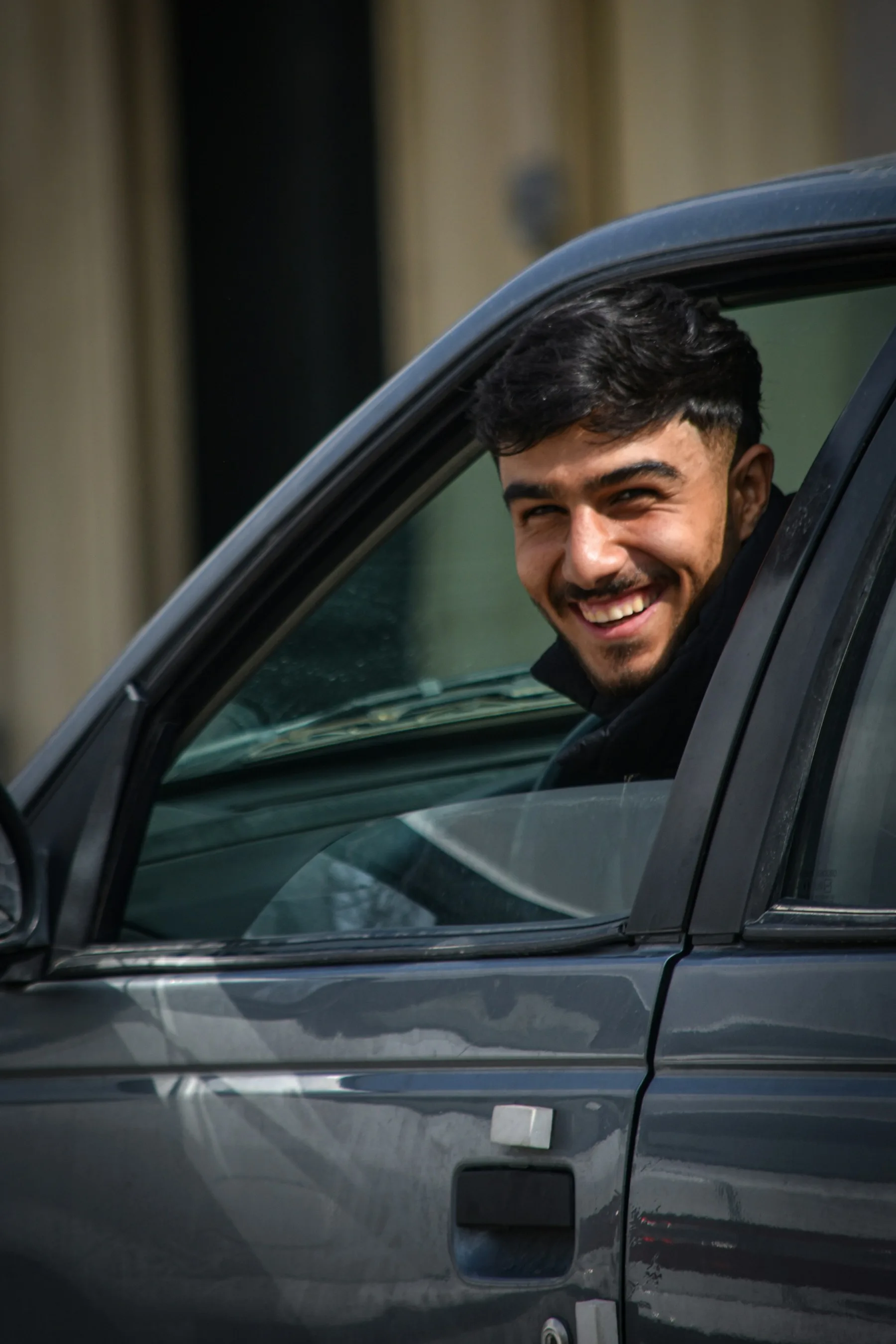 A smiling driver seated inside a car